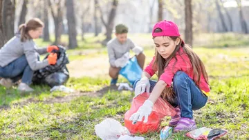 Fünf Kinder und ein Erwachsener stehen in einem hellen Museum mit einer Skulptur. Die Kinder haben Rucksäcke und bunte Kleidung an.