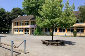 Der obere Schulhof mit einem Spielgerät und einer Sitzmöglichkeit.