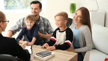 Eine Familie redet mit einer Beraterin am Tisch.