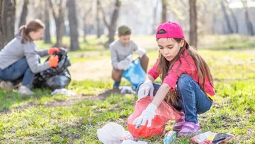 Fünf Kinder und ein Erwachsener stehen in einem hellen Museum mit einer Skulptur. Die Kinder haben Rucksäcke und bunte Kleidung an.