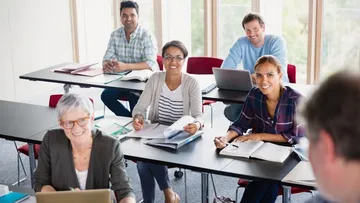 Kinder springen auf einer Wiese mit hoch erhobenen Armen. Der Himmel ist blau, und es gibt grüne Bäume. Sie tragen bunte Kleidung und lachen im Sonnenschein.